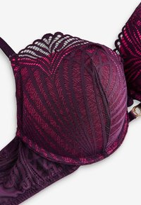 Sutien de culoare mov închis cu suprapunere de dantelă, prezentând modele geometrice detaliate în nuanțe variate de roz și margine zimțată.