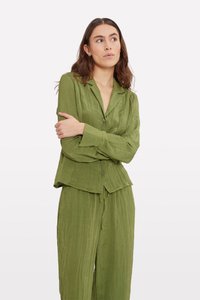 Olive green, textured button-up shirt with a collar and long sleeves. Paired with matching relaxed-fit pants, creating a coordinated outfit.