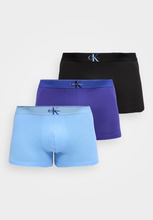 Tre mænds boxer briefs i sort, lilla og lyseblå, hver med en farvet taljebånd, der viser Calvin Klein-logoet.