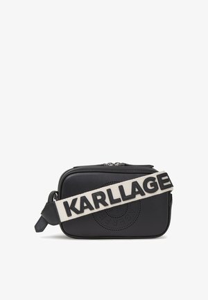 Bolso cruzado de piel negra con forma rectangular, que presenta un diseño de logo perforado y una correa en crema contrastante con la inscripción "KARLLAGE".