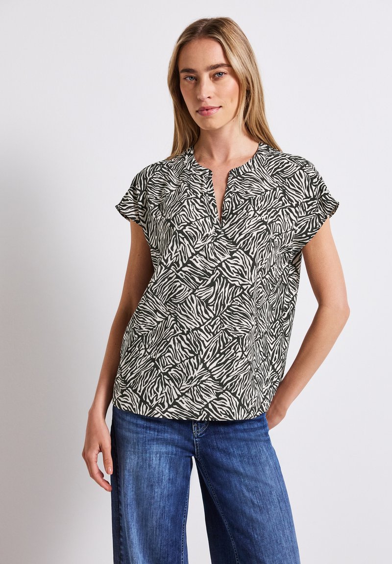 Blouse à manches courtes avec un motif zèbre noir et blanc, dotée d'un col en V et d'une coupe décontractée. Tissu léger avec une texture lisse.