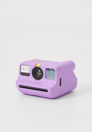 Purple Polaroid instant camera with rainbow stripe, lens, flash, viewfinder, and photo slot on a white background.