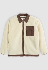 Chaqueta de forro polar blanca con un cuello marrón, cierre frontal y un bolsillo en el pecho con solapa. La textura es suave y de apariencia peluda.