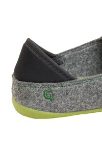 Grau gefütterter Schuh mit schwarzem Obermaterial aus Textil, grüner Außensohle und grünem gesticktem Logo. Abgerundete Form mit minimalen Nähten und Akzenten.