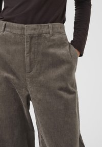 Olijfgroene corduroy broek met een wijd model, voorzien van verticale ribbeltextuur en zijzakken. De tailleband is plat en heeft riemlussen.