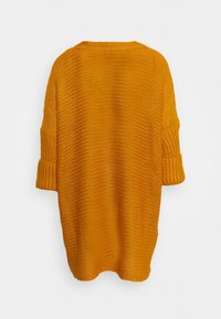 Stickad tröja i klargul, med lös passform, trekvartslånga ärmar och ett texturerat mönster. Ingen synlig hårdvara eller accenter.