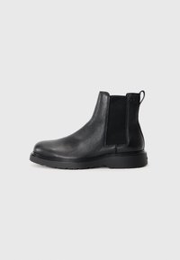 Black leather chelsea boots featuring a textured finish, elastic side panels, and a sturdy rubber sole. Subtle branding on the heel.