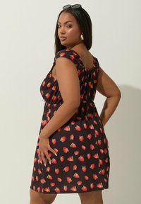 Czarna sukienka z krótkimi bufkami, z nadrukiem czerwonych truskawek. Materiał jest lekki, a elastyczny pas zapewnia luźny krój.
