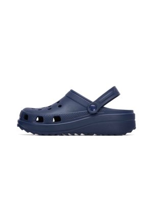 Zuecos ligeros de color azul marino hechos de caucho, con orificios de ventilación, una correa y una suela texturizada para mejorar el agarre. Diseñados para la comodidad y un uso fácil.