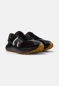 Black athletic shoes with a textured upper, contrasting white and gray accents, and a rubberized sole with a circular tread pattern.
