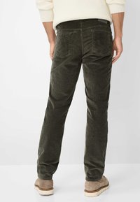 Donkergroene corduroy broek met een rechte pasvorm, twee achterzakken en een gestructureerde afwerking, gecombineerd met beige schoenen.