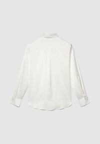 Blusa bianca a maniche lunghe con polsini e piega posteriore, mostrata distesa su uno sfondo grigio chiaro.