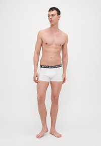 Fehér pamut boxer alsónemű fekete derékkal, amelyen a "justcavalli" logó található. Testhez simuló dizájn, sima textúra és combközép hosszúság.