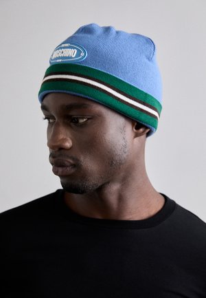 Svjetloplava pletena kapa s plavim i bijelim logom, sa zelenim, smeškim i bijelim prugama na dnu. Glatka tekstura, udobno prianjanje.