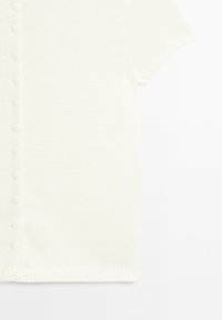 Biały, krótki sweter na guziki z dzianiny z półokrągłym wykończeniem, pokazany na białym tle.