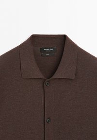 Polo in cotone marrone con colletto e due bottoni neri, etichettato Massimo Dutti prodotto in Cina.