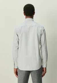 Hellgraues Langarmhemd mit Knopfkragen, glatter Textur, abgerundetem Saum und geknöpften Manschetten. Rückansicht gezeigt.