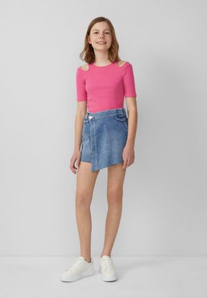 Roze geribbelde top met korte mouwen en uitsparingen op de schouders, gecombineerd met een lichtblauwe asymmetrische spijkerrok en witte sneakers.