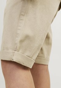 Beige katoenen shorts met omgeslagen pijpen en een zachte textuur. Bevat zichtbare zijnaad en stikseldetails langs het been.