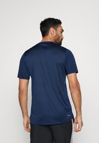 Camiseta deportiva de manga corta en azul marino, fabricada con un tejido suave que absorbe la humedad, con cuello redondo y detalles de costura sutiles en el dobladillo.