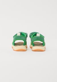 Green suede sandals with open back and adjustable straps; beige and orange outsole; textured footbed.