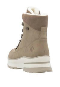 Botas impermeables color marrón con un suave forro de piel blanca, diseño de cordones, puntera redondeada y una gruesa suela de goma blanca con ranuras de tracción.