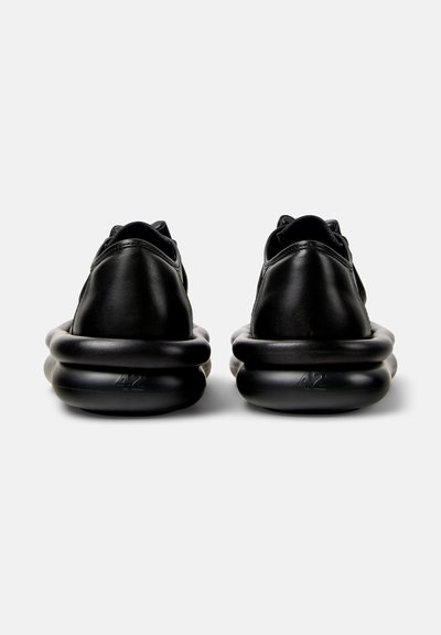 Sorte lædersneakers med en afrundet, polstret sål. Har et minimalistisk design og nummeret "42" prægede på hælen.