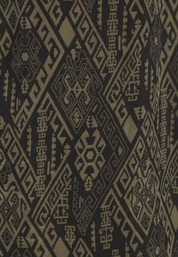 Svart tyg med intrikata geometriska mönster i mörkbrunt och beige, med diamanter och symboler som skapar textur och visuellt intresse.