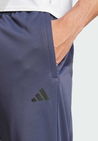 Pantalones cortos deportivos de color marino, hechos de una tela texturizada, con un bolsillo lateral y un logo negro de adidas en la pierna izquierda.