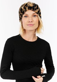 Luipaardprint fuzzy hoofdband in warme tinten. Zachte textuur met een gedraaid ontwerp aan de voorkant. Gecombineerd met een zwarte textuur lange mouwen top.