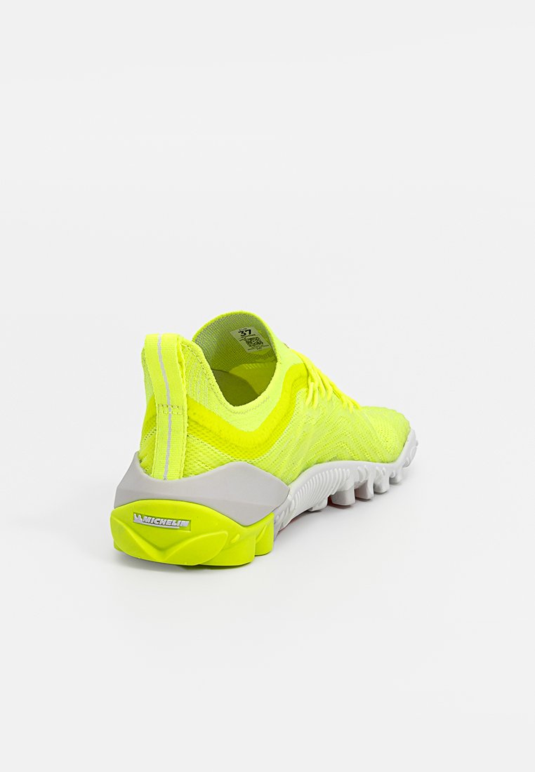 Zapatilla deportiva verde lima con parte superior de tejido texturizado, tacón de goma gris y marca Michelin en la suela. Diseño estructurado y flexible.