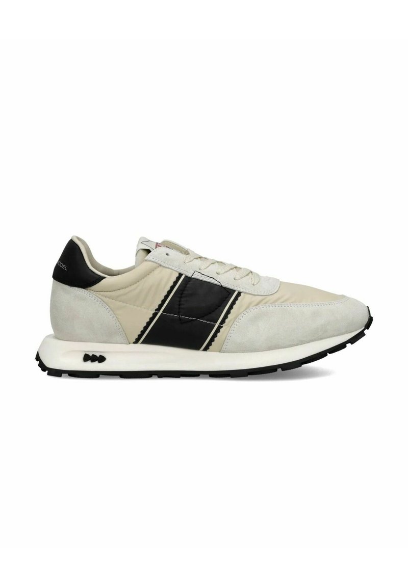 Lys beige løbesko med sorte detaljer. Overdel i suede og syntetisk materiale, teksturerede paneler og en gummisål med et markant slidbane.
