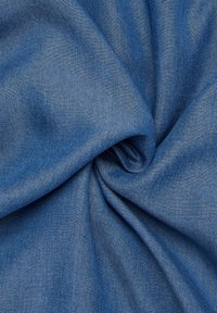 Tessuto denim di un blu intenso, che presenta una texture liscia con un sottile motivo a spina di pesce e un morbido drappeggio, piegato per rivelare profondità e lucentezza.