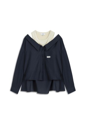 Námořnická košile na knoflíky s oversized límcem, vrstvená přes krémový ribbed pletený top. Obsahuje malé logo na přední straně.