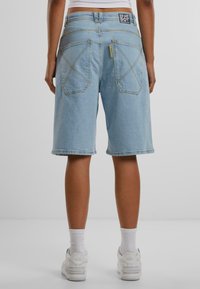 Svetlomodré denim šortky s voľným strihom, s detailmi šitia na zadných vreckách a logom na páse.