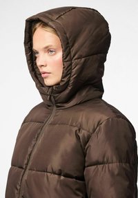 Chaqueta de plumas marrón con un cuello alto y capucha. Hecha de un tejido acolchado y brillante. Presenta un cierre frontal con cremallera y un detalle de costura mínimo.