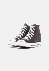 Grijze suède hoge sneakers met witte veters, rubberen neuskap en een textuurrijke zool. Heeft een witte tussenzool met zwarte strepen.