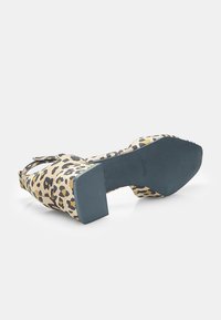 Leopard print high-heeled shoe with a thick block heel, open back, and textured sole. Color scheme includes beige, black, and brown patterns.