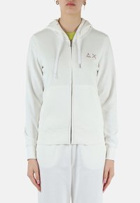 Felpa bianca con zip in tessuto morbido e cappuccio, caratterizzata da un piccolo logo sul petto, polsini a coste e una vestibilità rilassata.