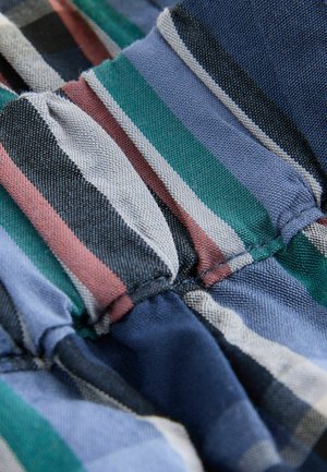 Pruhovaná látka s úzkymi pásikmi zelenej, modrej, čiernej a ružovej farby. Materiál pôsobí textúrovaným dojmom s našitým záhybom.