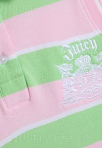 Detailný záber na ružové a zelené pruhované tričko s golierom, bielymi gombíkmi a vyšívaným bielym logom "Juicy" na hrudi.