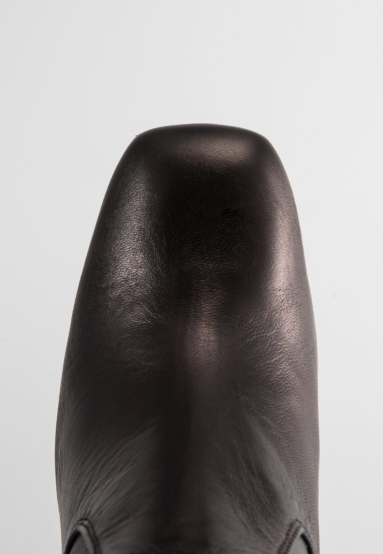 Schwarzer Lederschuh mit runder Spitze, glatter Oberfläche und minimaler Naht. Das Obermaterial hat ein elegantes Design, das moderne Einfachheit betont.