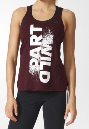 Femme portant un débardeur bordeaux sans manches avec le texte blanc audacieux "PART DIAL" et un pantalon de sport noir à rayures blanches.