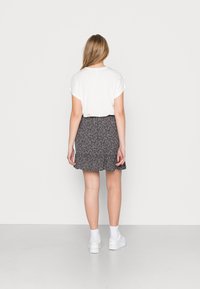 T-shirt branco de manga curta combinado com uma saia floral azul-marinha com bainha em formato de onda, completado com sapatilhas brancas e meias até ao tornozelo.