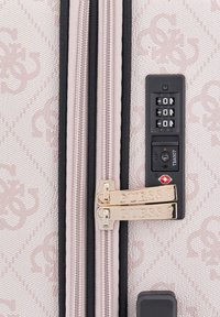 Valigia a fantasia rosa con due cerniere dorate, con marchio "GUESS" e una combinazione nera laterale. Superficie in tessuto testurizzato.