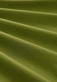 Diep olijfgroene katoenen stof met een zachte textuur, gevouwen in zachte golven, met subtiele variaties in kleur en lichtreflectie.