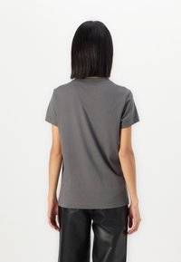 Camiseta gris de manga corta hecha de algodón. Diseño simple con cuello redondo. Textura suave, corte relajado y sin patrones visibles.