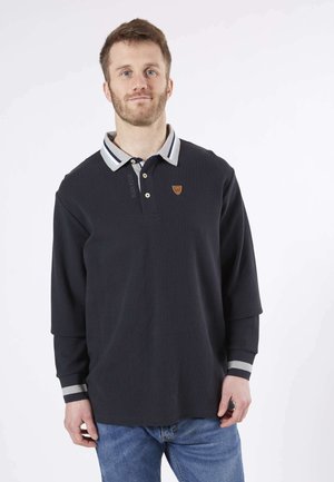Polo shirt à manches longues bleu marine foncé avec un col rayé, patte de boutonnage et écusson en cuir avec logo sur la poitrine. Fabriqué en tissu texturé.
