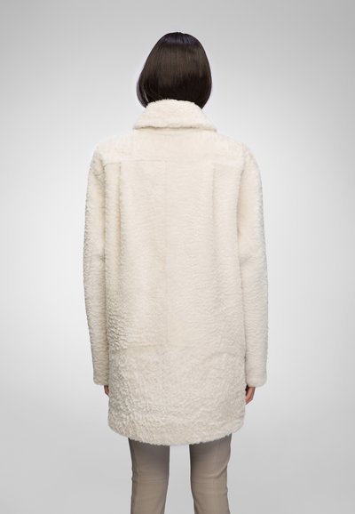 Cappotto in pelo sintetico bianco con colletto, caratterizzato da una superficie morbida e testurizzata. Ha una vestibilità comoda e arriva a metà coscia. Vista posteriore.