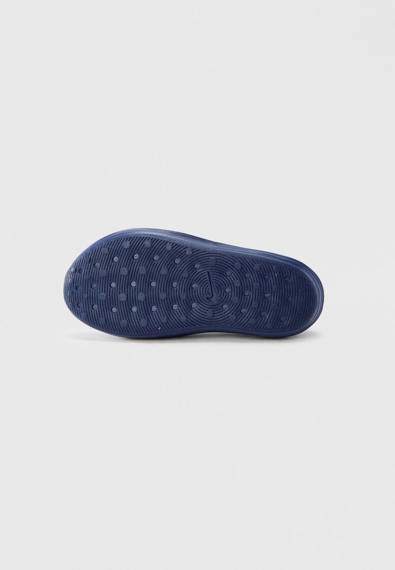 Blue rubber shoe sole featuring a textured pattern with circular grips and ridges for traction. Smooth edges and rounded toe design.